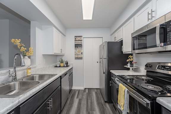 A modern kitchen with black appliances and white cabinets at Indian Lookout Apartments, West Carrollton, Ohio