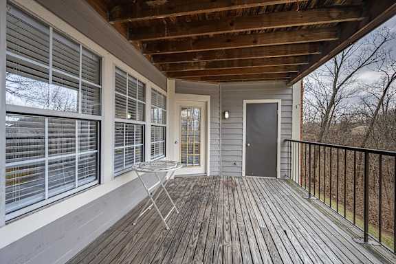 A wooden deck with a table and chairs and a sliding glass door at Indian Lookout Apartments, Ohio