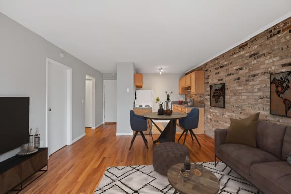 a furnished living room with a brick accent wall and a dining room table with four chairs at Cincinnati Premier Living*, Cincinnati, 45213