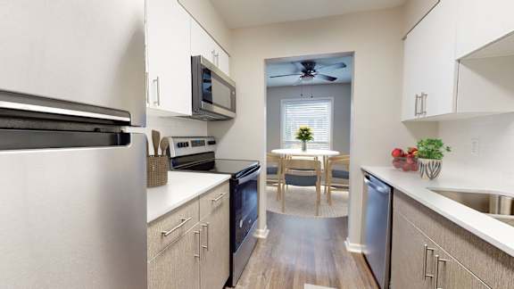 A kitchen with a refrigerator, microwave, oven, and sink.