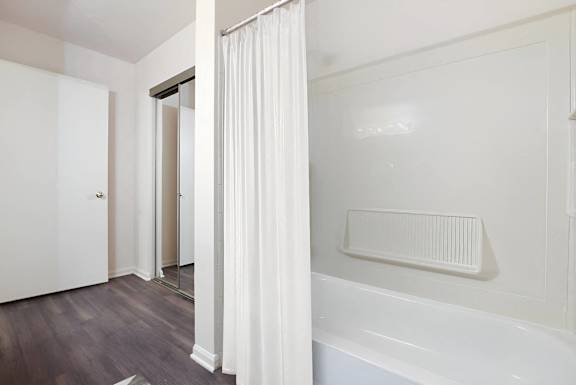 A white bathroom with a white tub and a white shower curtain.
