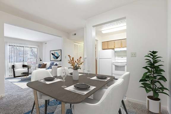 A dining room with a table set for two and a potted plant.
