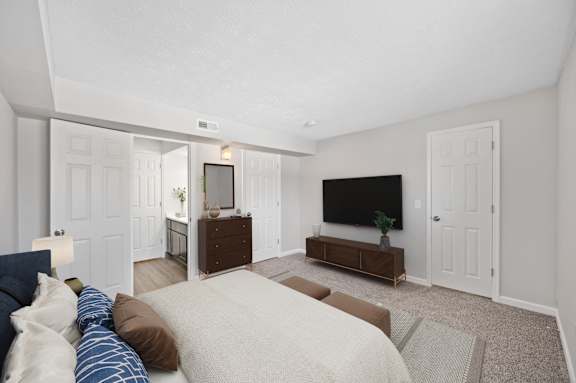 A bedroom with a bed, dresser, and tv.