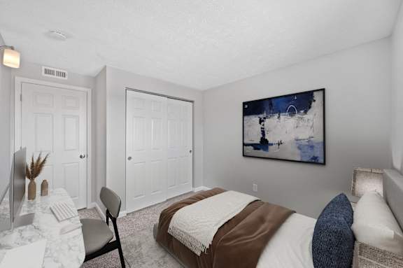 A bedroom with a bed, a desk, and a painting on the wall.