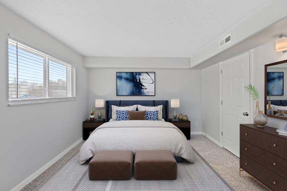 A bedroom with a large bed and a painting on the wall.