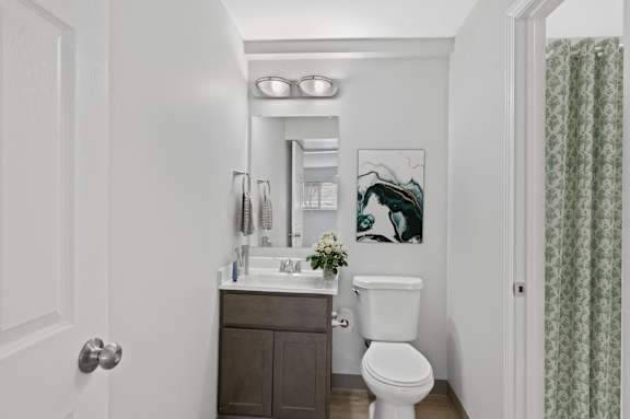 A white toilet sits in a bathroom next to a sink and a mirror.