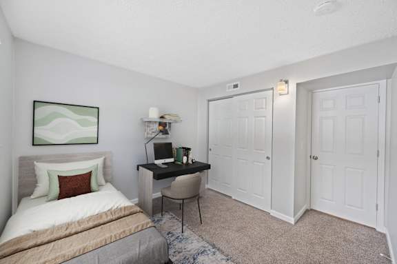 A bedroom with a bed, desk, and chair.
