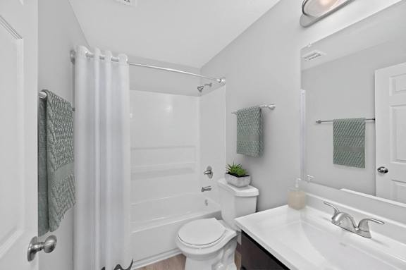 A white bathroom with a toilet, sink, and shower.