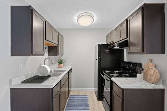 A kitchen with black appliances and brown cabinets.