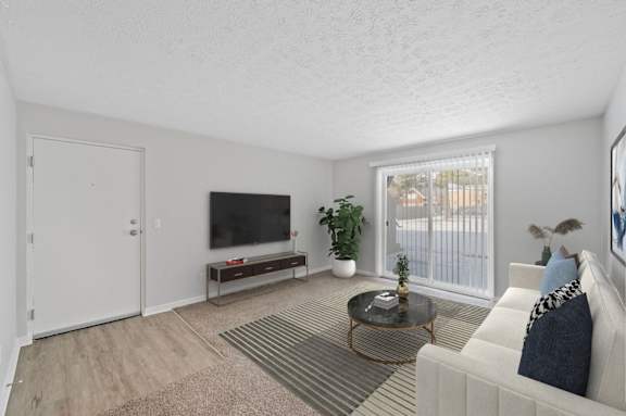 A living room with a white couch, a coffee table, and a flat screen TV.