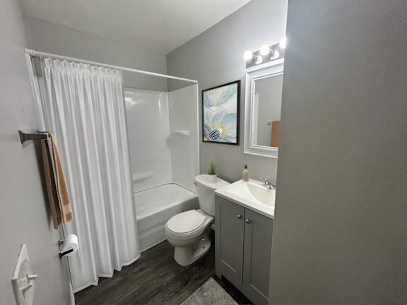 A small bathroom with a toilet, sink, and shower.