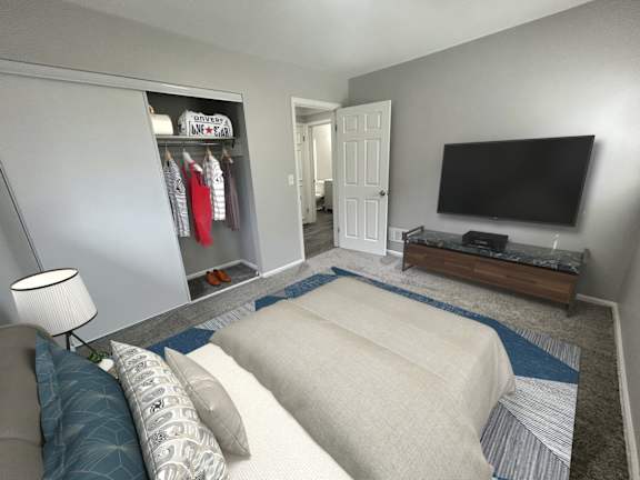 A living room with a couch, a television, and a clothing rack.