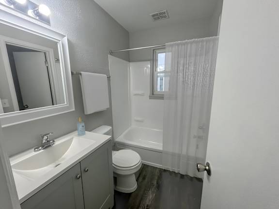 A white bathroom with a toilet, sink, and shower.