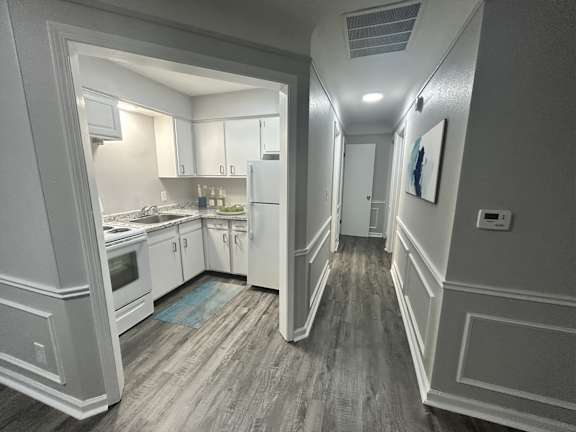 A kitchen with white appliances and cabinets is shown.