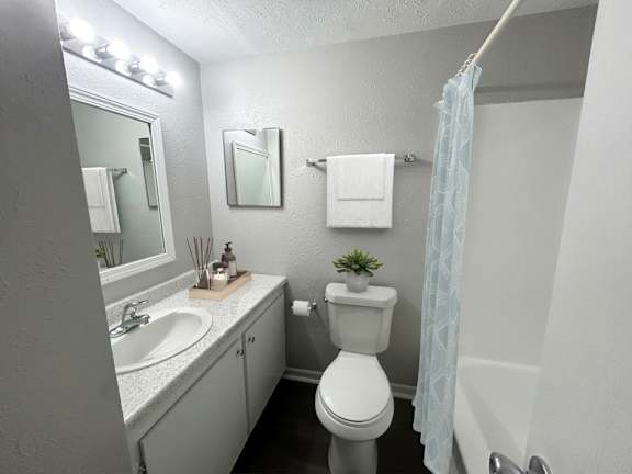 A small bathroom with a toilet, sink, mirror, and lights.