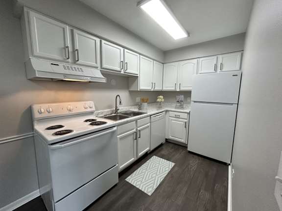 A white kitchen with a stove, sink, and refrigerator.