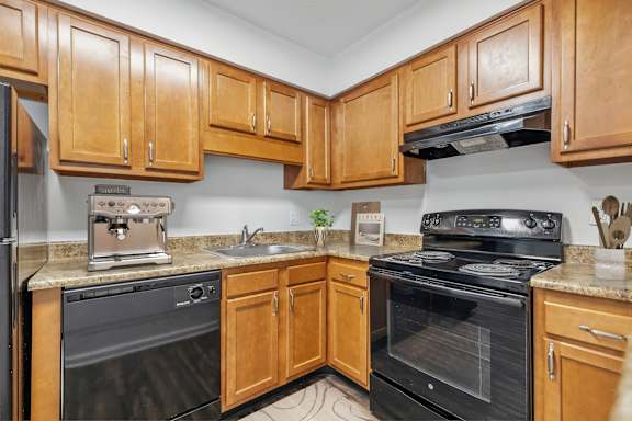 A kitchen with wooden cabinets and black appliances.