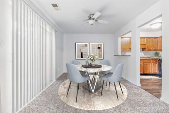 A dining room with a round table and grey chairs.