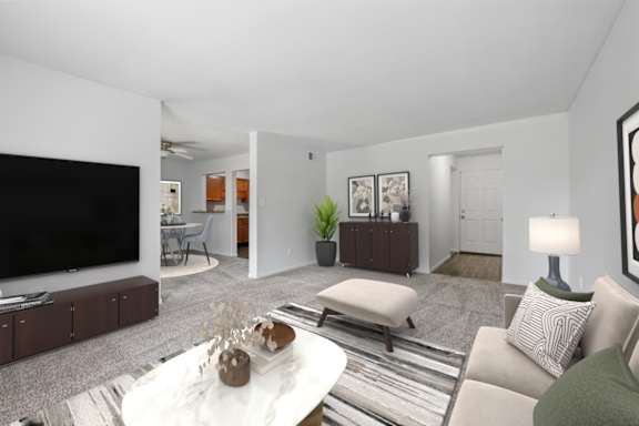 A living room with a white couch, a coffee table, and a television.
