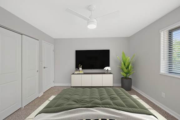 A bedroom with a bed, a television, and a plant. at Indian Creek Apartments*, Ohio, 45236