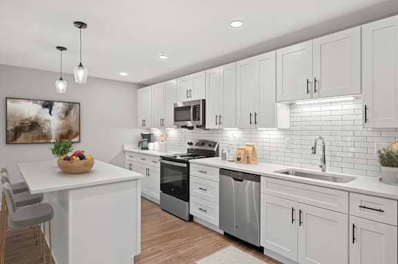 A modern kitchen with white cabinets and a wooden table. at Indian Creek Apartments*, Cincinnati, OH, 45236