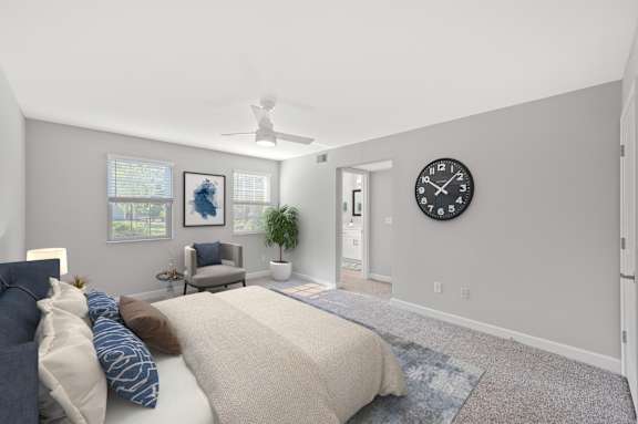 A bedroom with a bed, pillows, a ceiling fan, a chair, a potted plant, and a clock on the wall. A bedroom with a bed, pillows, a ceiling fan, a chair, a potted plant, and a clock on the wall. at Indian Creek Apartments*, Cincinnati, OH