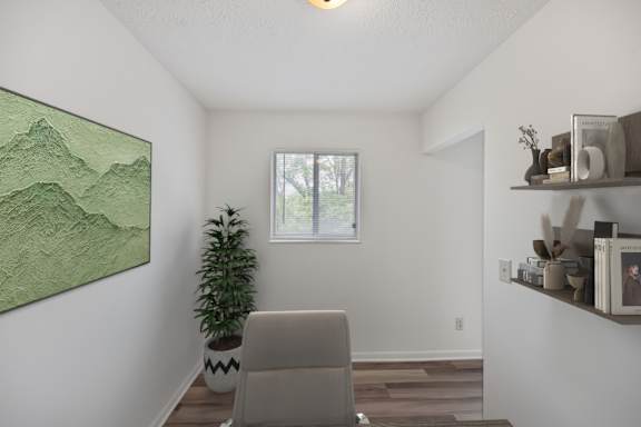 A room with a painting, a plant, and a chair.