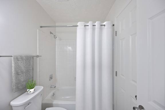 A white bathroom with a toilet, sink, and shower.