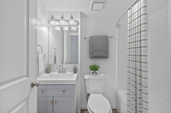 A white bathroom with a toilet, sink, and mirror.