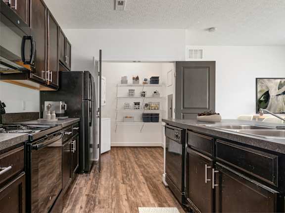 A kitchen with dark wood cabinets and a black refrigerator. at River View at Bexley Apartments, River View at Bexley