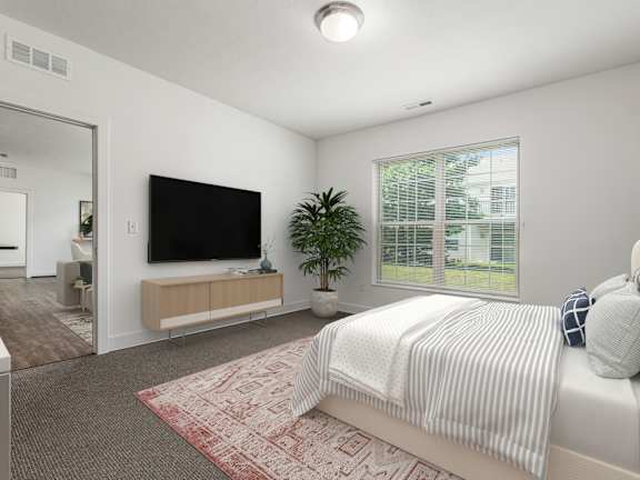 A bedroom with a bed, a television, and a plant. at River View at Bexley Apartments, River View at Bexley, OH, 43209