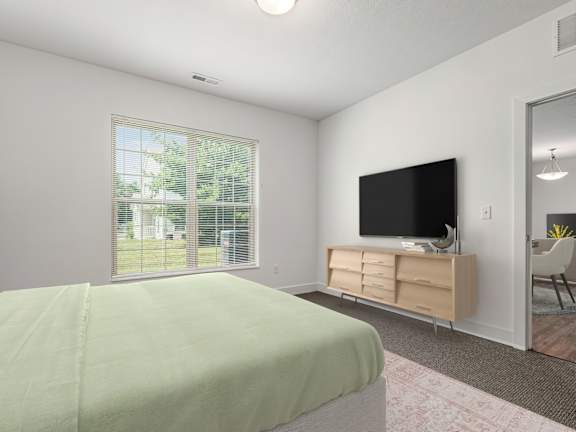 A bedroom with a bed, a television, and a window with blinds. at River View at Bexley Apartments, River View at Bexley, OH