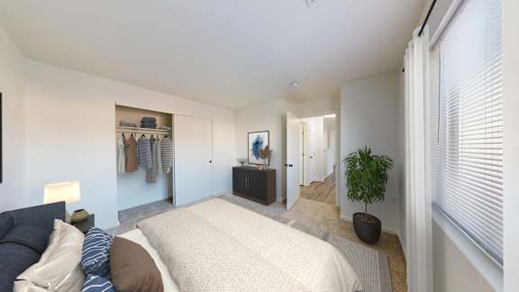 A bedroom with a bed, a potted plant, and a wardrobe.