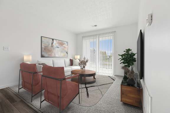 A living room with a white couch, two red chairs, and a painting on the wall.