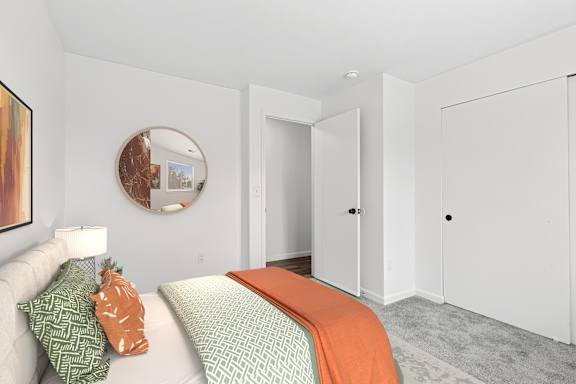 A bedroom with a bed, a couch, and a painting on the wall.