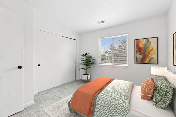 A bedroom with a bed, pillows, and a window.