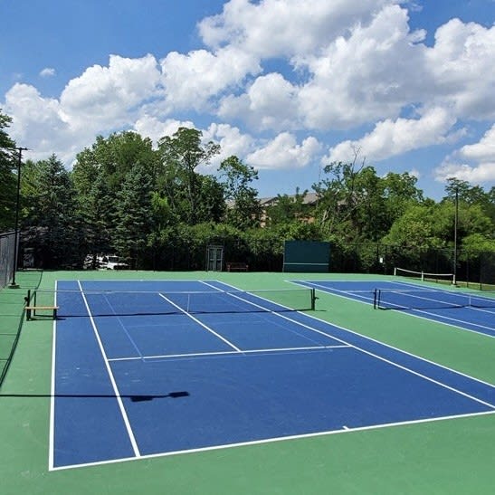 a blue and green tennis court with a blue sky at Indian Creek Apartments*, Cincinnati, OH
