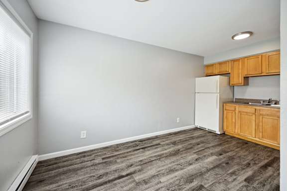 A kitchen area with a white refrigerator and wooden cabinets.