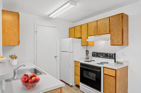 A kitchen with wooden cabinets and a white stove top oven.