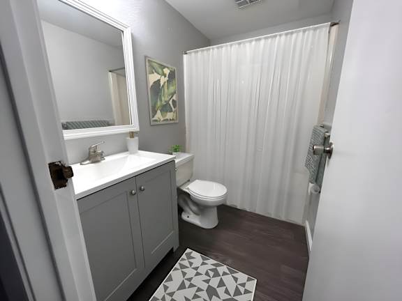A bathroom with a white sink, toilet, and shower curtain.
