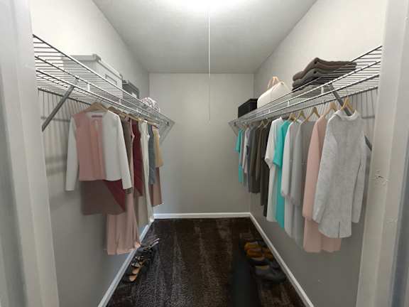 A walk in closet with clothes hanging on racks.