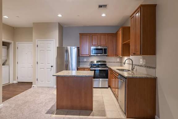 Open kitchen with stainless steel appliances and island at Renaissance at the Power Building Apartments, Cincinnati