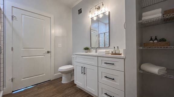 A white bathroom with a toilet, sink, and mirror.