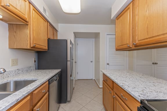 Kitchen with wood cabinets and granite counter tops and a black refrigerator at Indian Creek Apartments, Cincinnati, OH, 45236