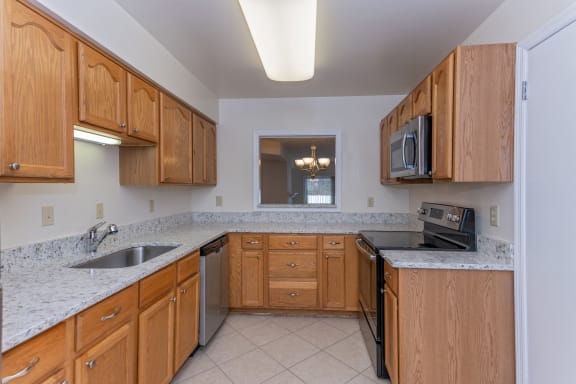 a kitchen with wooden cabinets and granite counter tops and a sink at Indian Creek Apartments*, Cincinnati