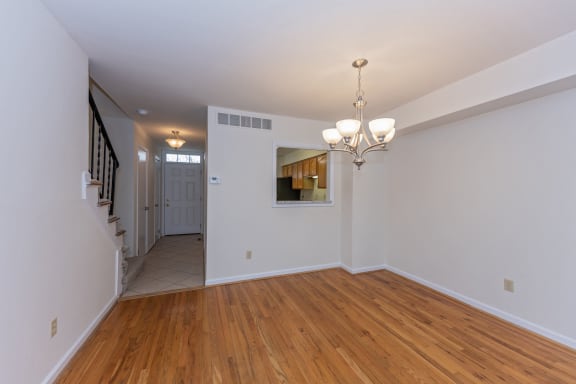 a living room with a hard wood floor and white walls and a staircase at Indian Creek Apartments*, Cincinnati, OH