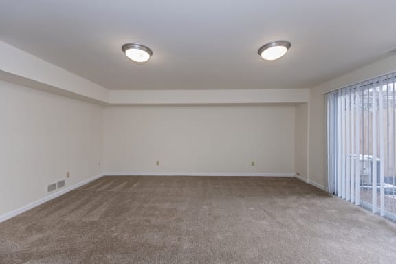 an empty living room with a large window and carpet at Indian Creek Apartments*, Ohio