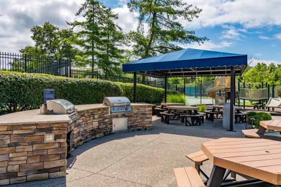 a picnic area with picnic tables and a blue roofed pavilion with a playground at Indian Creek Apartments*, Ohio, 45236