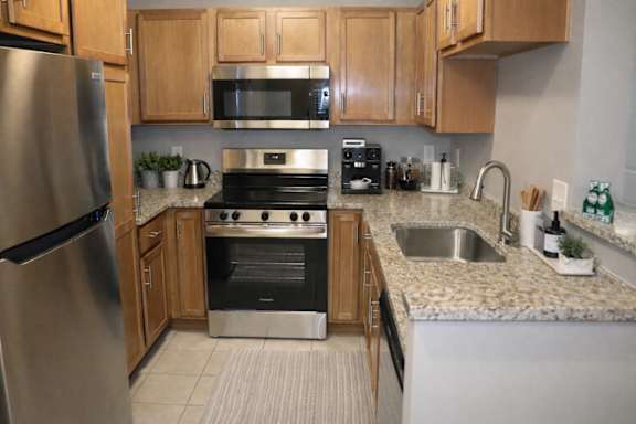 A kitchen with a stainless steel refrigerator, microwave, oven, and sink.