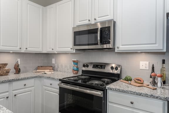 Kitchen with white cabinets and a stove and microwave